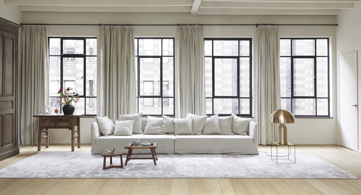 Frankly Amsterdam rug in a light-filled living room with white linen sofa, wooden side table and antique cabinet